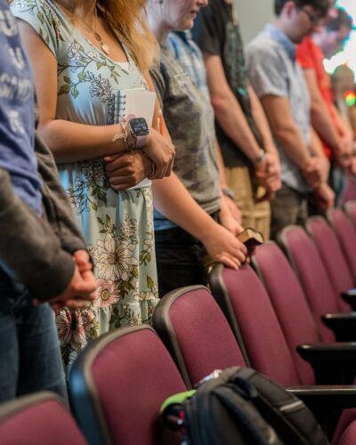 A row of students in chapel, heads bowed during prayer. 