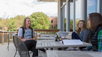 Three students sitting outside while discussing
