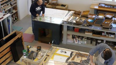 A man cutting a sheet of wood in a wood shop