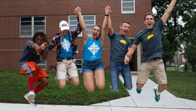 A group of students jumping while holding hands