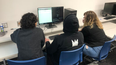 Students gathered around a computer at a programming competition