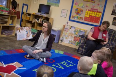 A Concordia student reading a picture book to children at St. John's Child Development Center