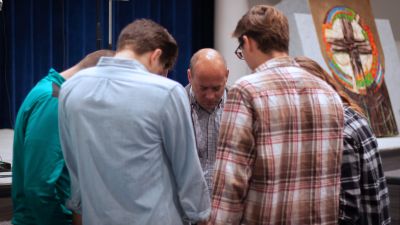 Pastor Matthias praying with a group of students