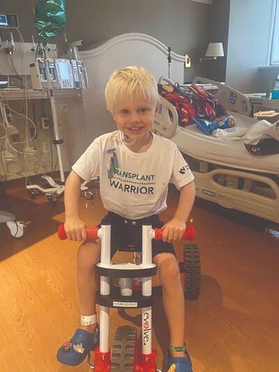 Paxton sitting on a tricycle in his hospital room. 