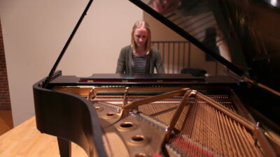 Looking across a Steinway grand piano with a student playing.