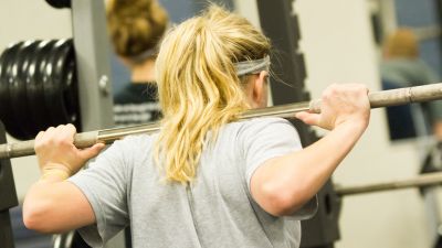 A woman doing squats with a weighted barbell
