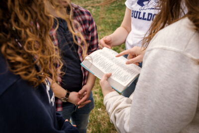 A group of students reading the Bible outdoors