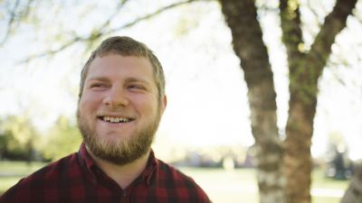 A smiling student standing in front of a tree