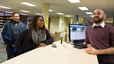 A student talking to a librarian at the library front desk