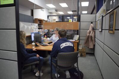 Two students in a meeting looking at a computer screen while a staff member points to information on the screen. 