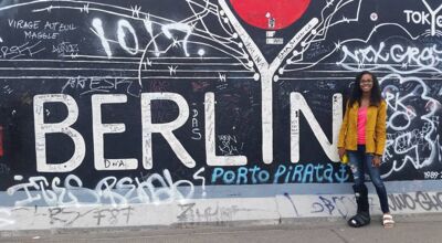 A student standing in front of a graffiti wall mural that says Berlin. 