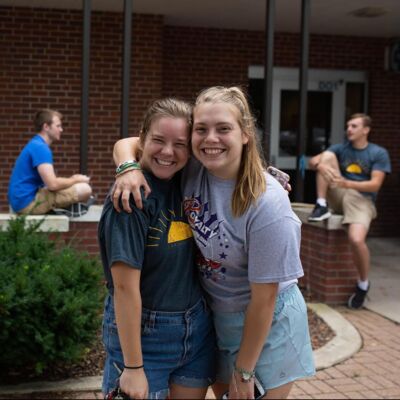 Two students hugging in front of a dorm building