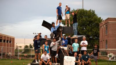 students pose in front of the Son of Man Be Free statue at Concordia University, Nebraska