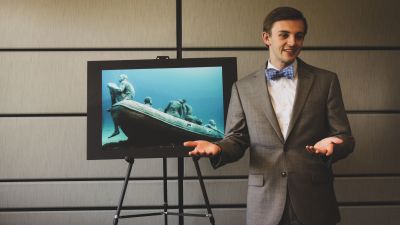A student giving a speech in front of a computer screen