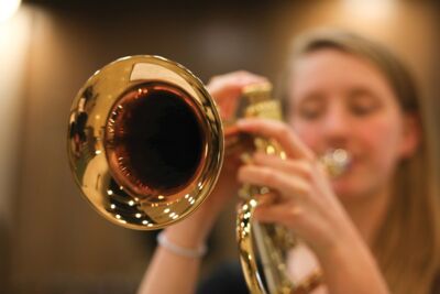 Close up of the horn end of a brass instrument a music student is playing