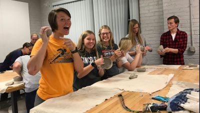 Members of the art club shaping clay into bowls. 