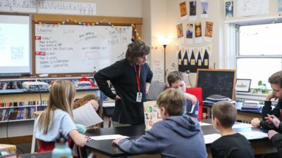 A middle school teacher looking over a student's work during class