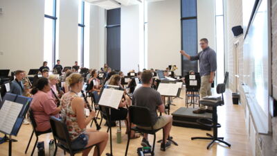 Music professor leading the wind symphony during rehearsal.