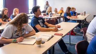 A classroom full of students taking notes during a lecture