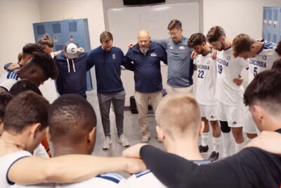 Campus pastor praying with the men's soccer team before a game
