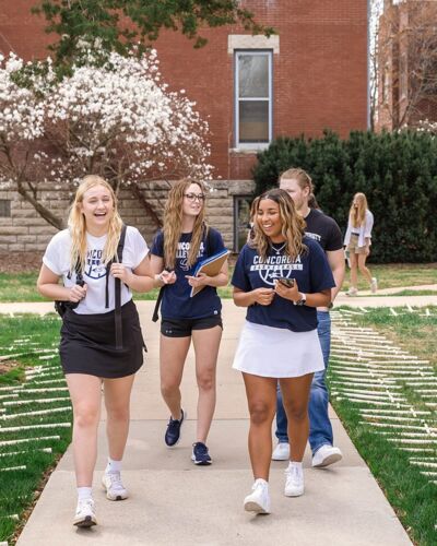 Four students walking through the quad and laughing with each other. 