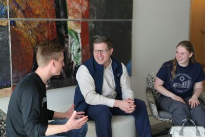 Two students laughing with a professor outside class