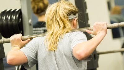 A student doing a squat with weights