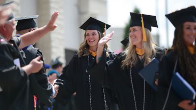 Two female Concordia graduates celebrate during the commencement recessional