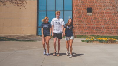 Three students laughing while walking through the Plaza.