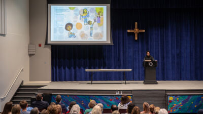 A teacher giving a lecture to a middle school class in Weller Chapel
