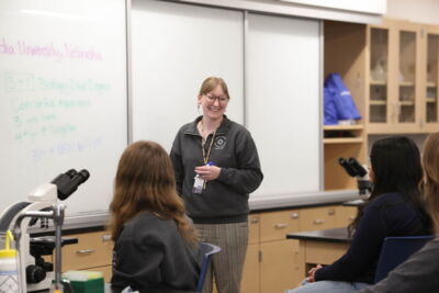 A smiling professor interacting with students in a class