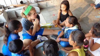 A student sitting in a circle while talking to children while on a foreign trip