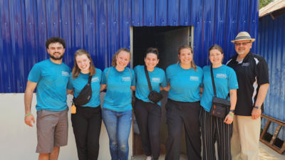 Jose Sanchez, Aubrey Baumann, Kyla Schleusener, Sydni Kroll, Ashley Gerczynski, Mady Payne, and Dr. Curt Beck in front of the rice bank they helped to fund with Garuna Ministries.