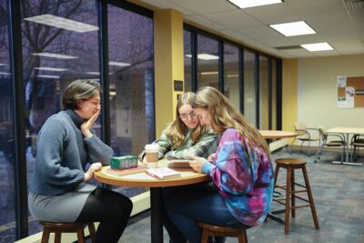 Students from the Luke Scholars program conversing about a book in the library