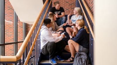 Students sitting in the stairwell of Thom, studying flashcards 
