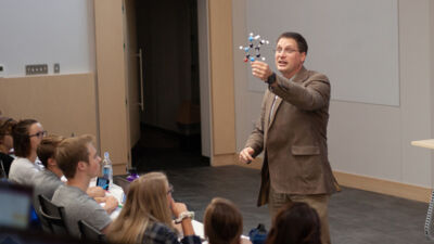 Science professor holding up a model of a molecule in class.