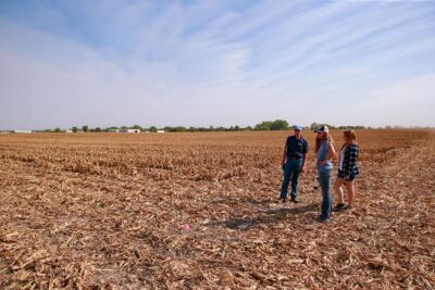 Ag Science Professor Dr. Dennis Brink with two students surveying a corn field. 