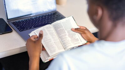 A student reading the Bible at a desk. 