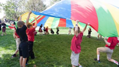 Elementary students play with a parachute 